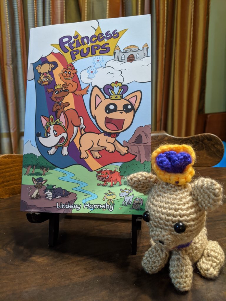A handmade crocheted toy puppy is next to the Princess Pups book